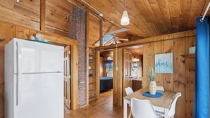 A wooden interior with a refrigerator, dining table, chairs, and a ceiling fan. - Atlantis Motel (Old Orchard Beach)