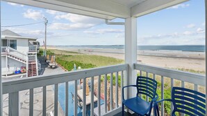 A balcony with a view of the beach, a pool, and a house with a staircase. - Atlantis Motel (Old Orchard Beach)