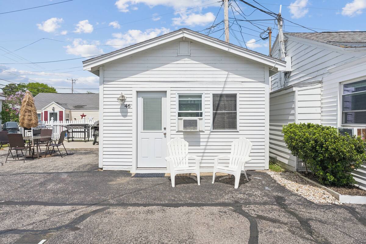 A small, single-story building with a white exterior, a door, and two windows.