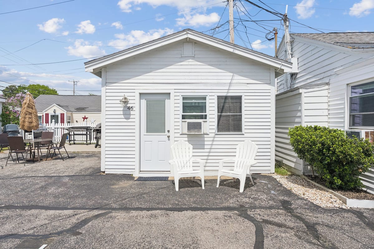 A small, single-story building with a white exterior, a door, and two windows.