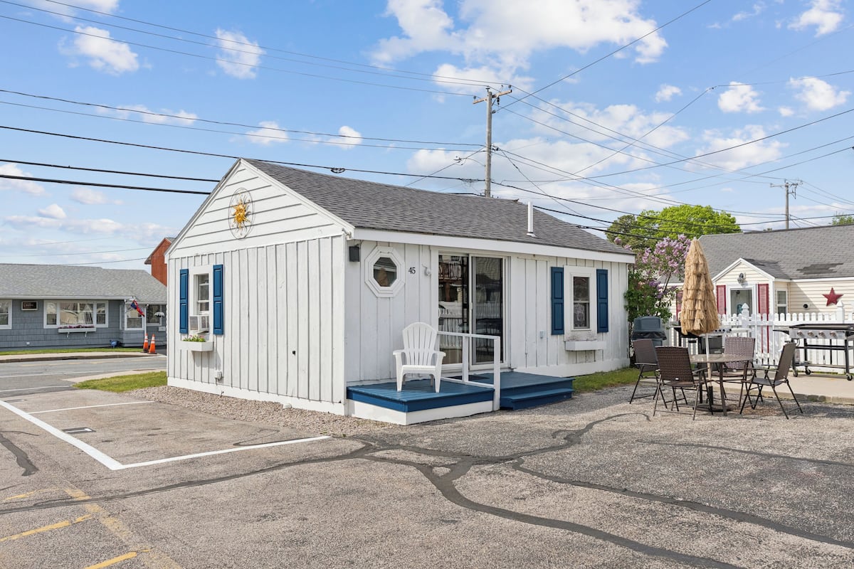 A small white building with a porch and outdoor seating area.