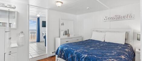 Quarto com cama, mesa de cabeceira, cômoda, espelho e um letreiro que diz 'Seashells'.