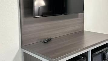 Un televisor de pantalla plana montado en la pared sobre una encimera de cocina con microondas y lavavajillas debajo.