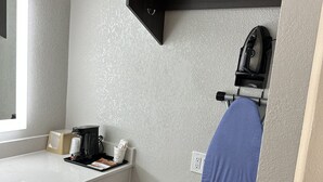 A modern bathroom with a white countertop, a coffee maker, a trash bin, and a towel rack with a blue towel. - Sleepy Traveler Motel (Wagoner)
