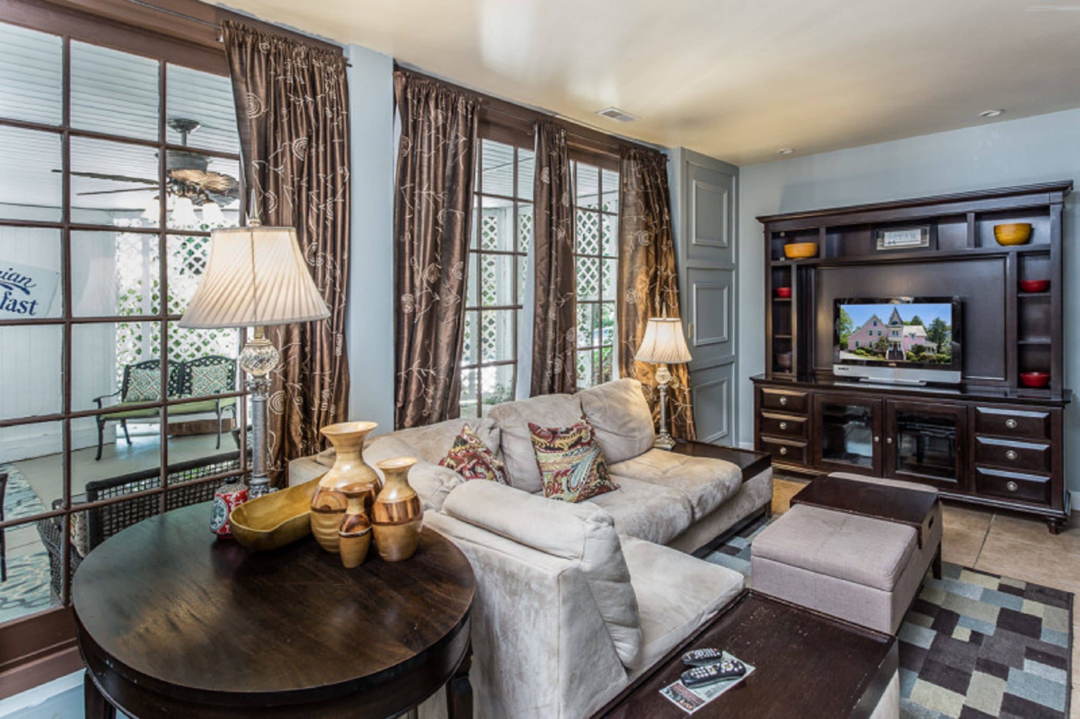 A living room with a sofa, two lamps, a coffee table, a TV, and a cabinet.