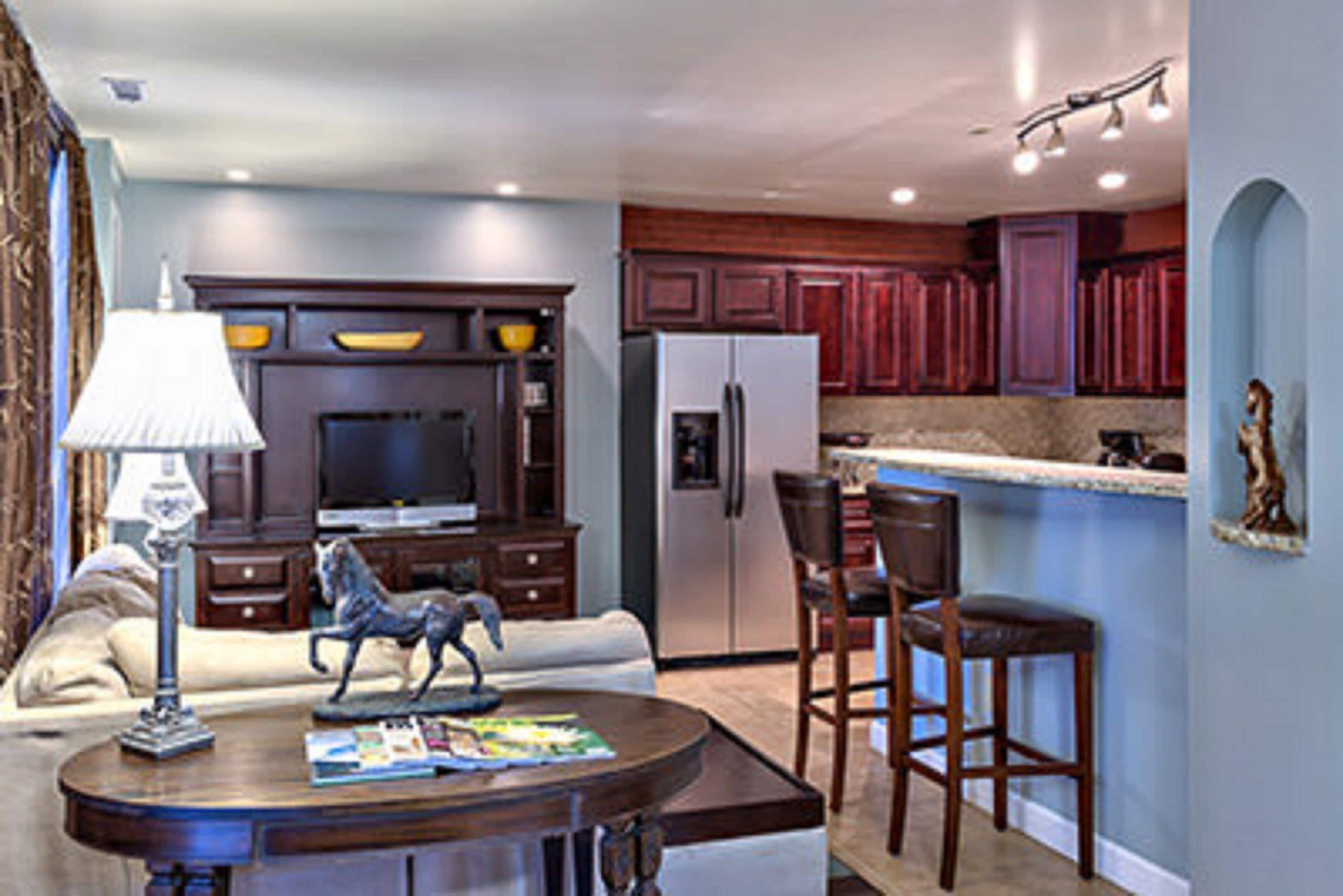 A modern kitchen with dark wooden cabinets, a built-in oven, and a refrigerator.