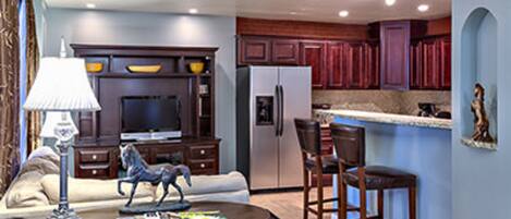 A modern kitchen with dark wooden cabinets, a built-in oven, and a refrigerator.