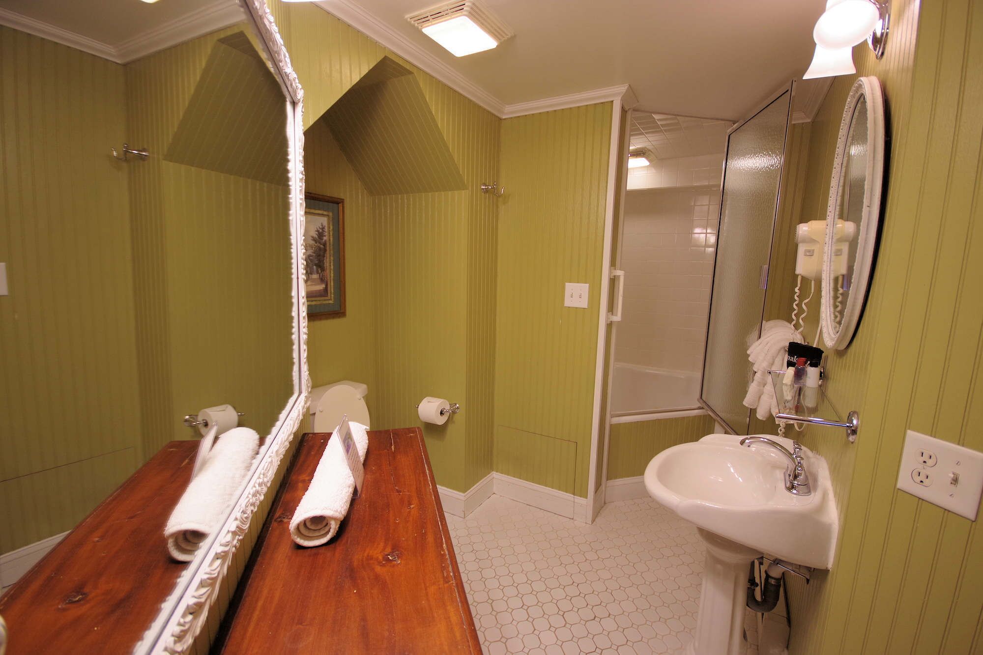 A bathroom with a wooden vanity, a white sink, and a mirror.