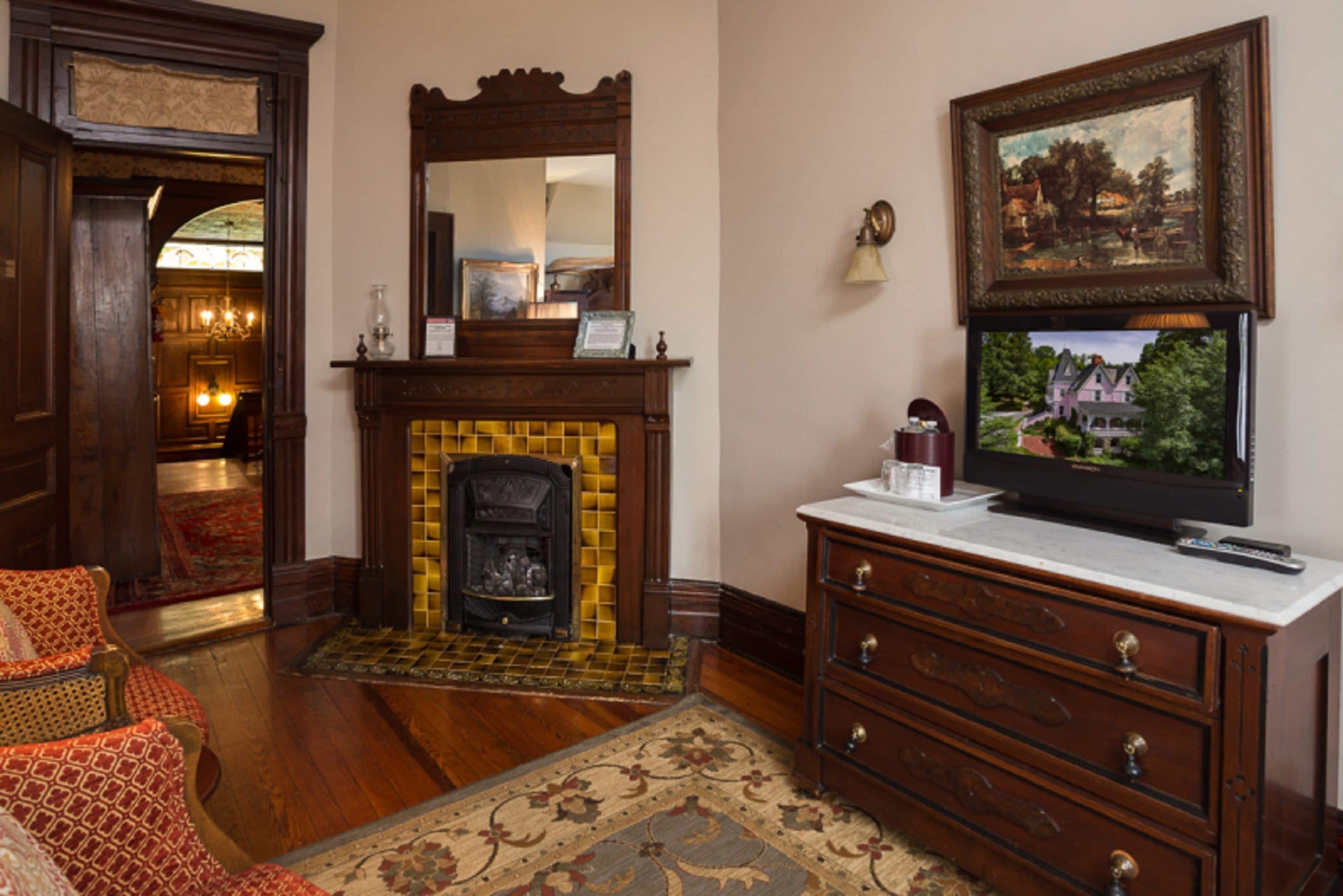 Um quarto com lareira, móveis de madeira, televisão e um quadro na parede.