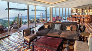 A spacious lounge area with a large sofa, armchairs, and a bar area with shelves. - DoubleTree by Hilton Goa-Panaji (Panaji)