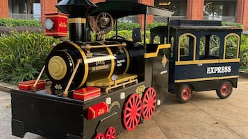 Eine alte Dampflokomotive mit dem Schriftzug "GN ENTERPRISES" und "EXPRESS" an der Seite, geparkt vor einem Gebäude mit roten Backsteinsäulen und Balkonen.