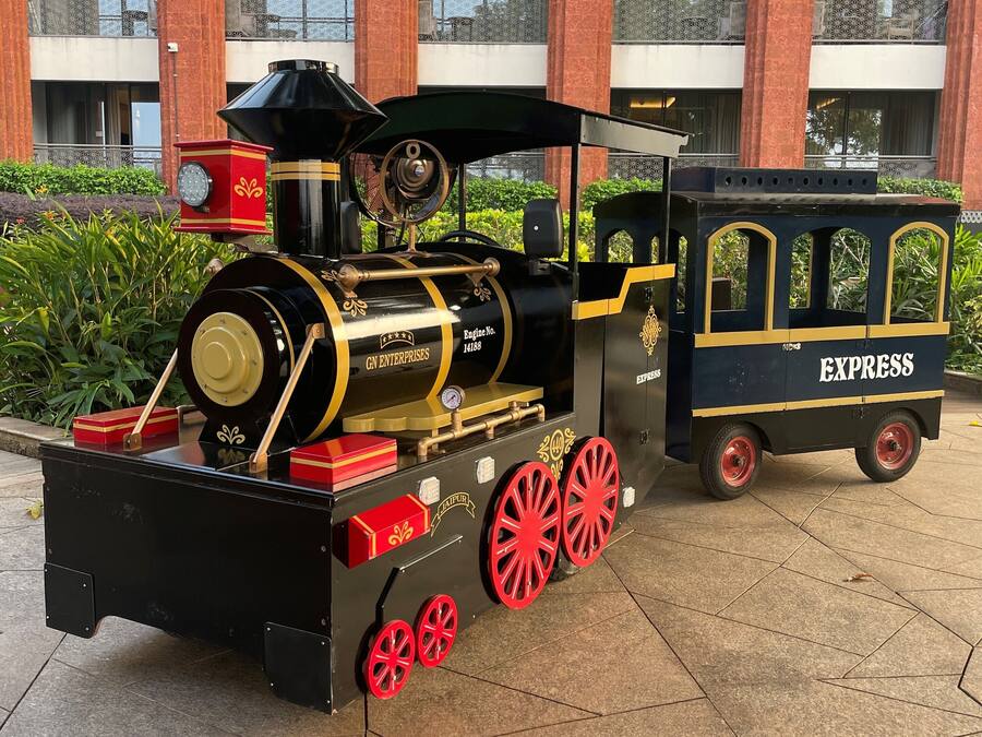 Eine alte Dampflokomotive mit dem Schriftzug "GN ENTERPRISES" und "EXPRESS" an der Seite, geparkt vor einem Gebäude mit roten Backsteinsäulen und Balkonen.