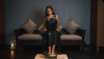 A woman standing on a platform with a bowl in front of a sofa and a sign that reads "ELLE spa & salon".