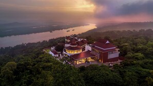 An aerial view of a hotel with a central dome structure, surrounded by lush greenery and a lake. - DoubleTree by Hilton Goa-Panaji (Panaji)