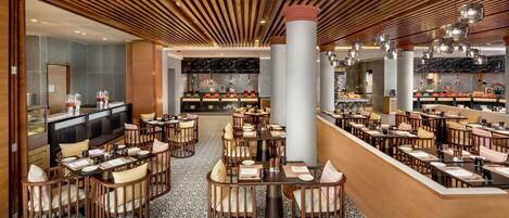 Un restaurante espacioso con varias zonas de comedor, techo de madera y suelo de baldosas estampadas.