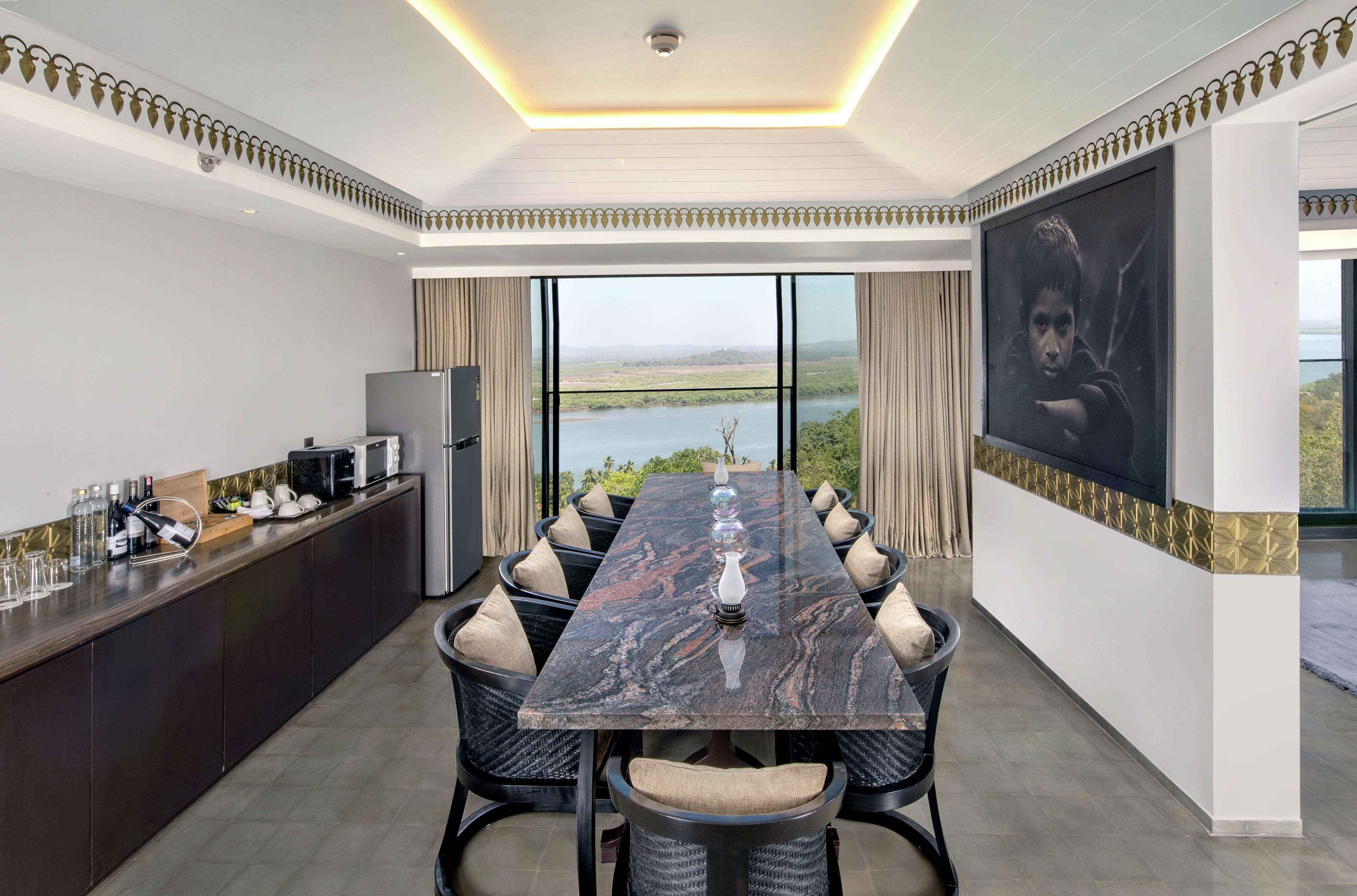 Un espace repas moderne avec une table en marbre, des chaises noires et une vue sur un lac.