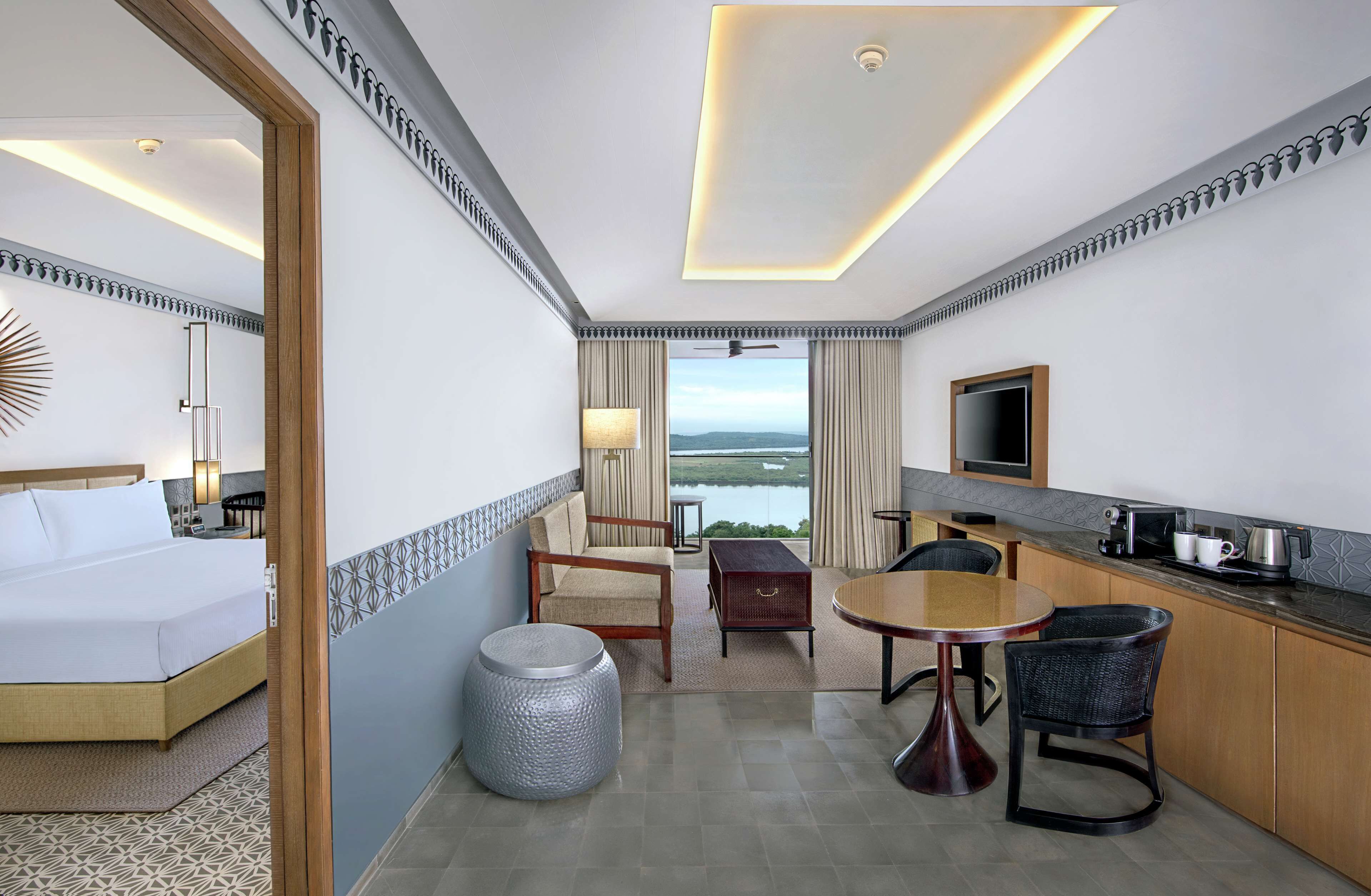 Een hotelkamer met een bed, een eethoek, een keuken en uitzicht op de omgeving.