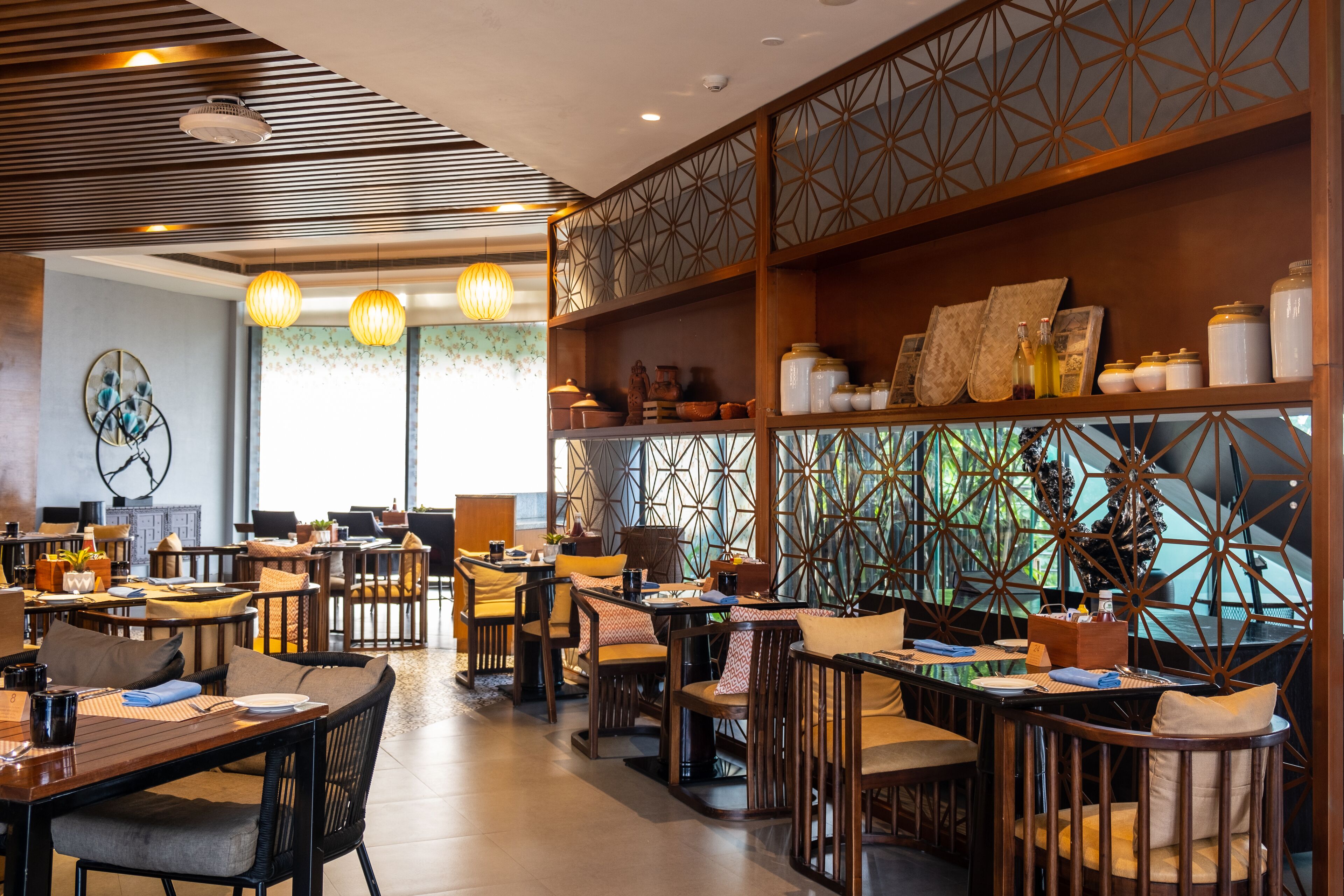 Un restaurante con varias mesas y sillas, decoración de madera y una pared con diseño geométrico.