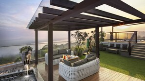 A rooftop terrace with a white wicker sofa, a small table with drinks, and a view of the cityscape. - DoubleTree by Hilton Goa-Panaji (Panaji)
