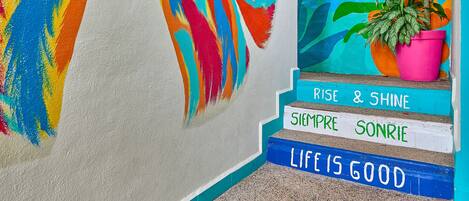 Una escalera con murales coloridos y frases motivadoras.