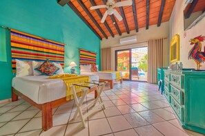 Una habitación con dos camas, ventilador de techo, suelo de baldosas y vista a través de una puerta.