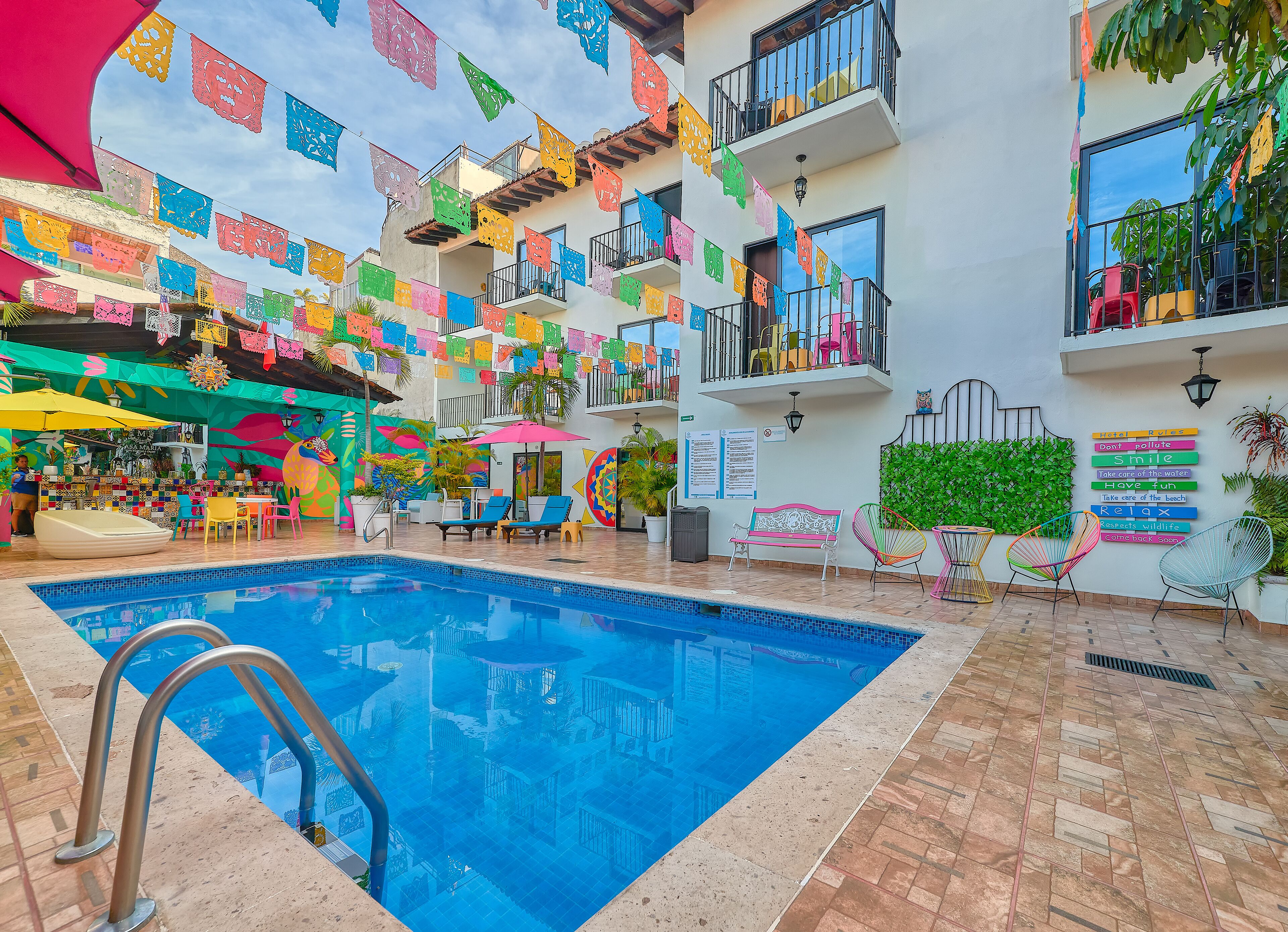 A pool area with colorful paper decorations, a bar, and outdoor seating.