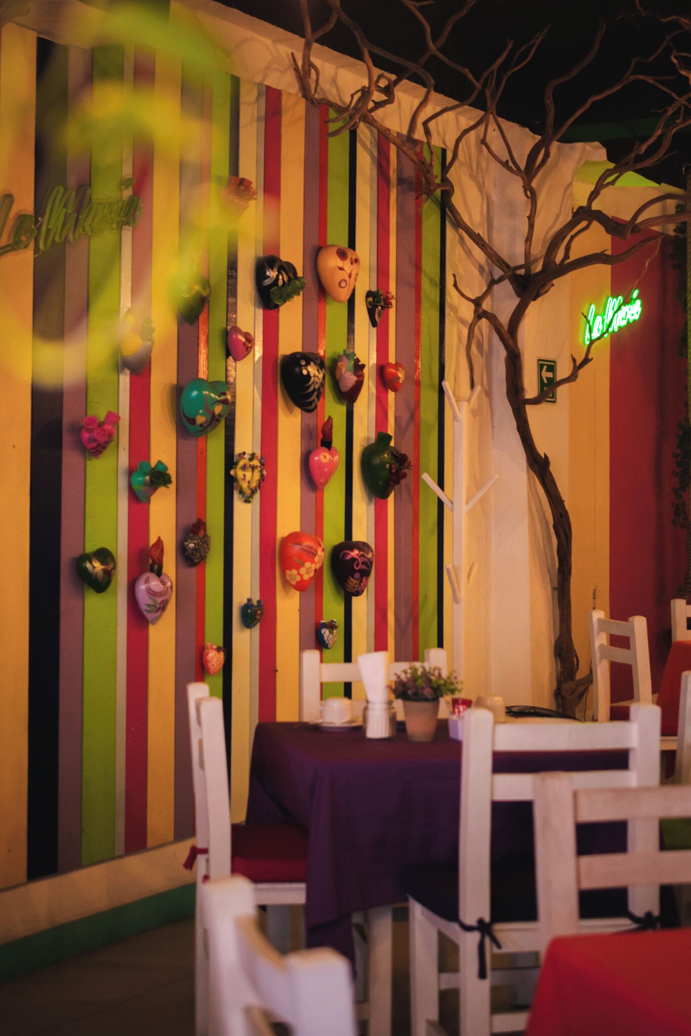 Ein Restaurant mit einer farbenfrohen, gestreiften Wand und einem Neonlicht.