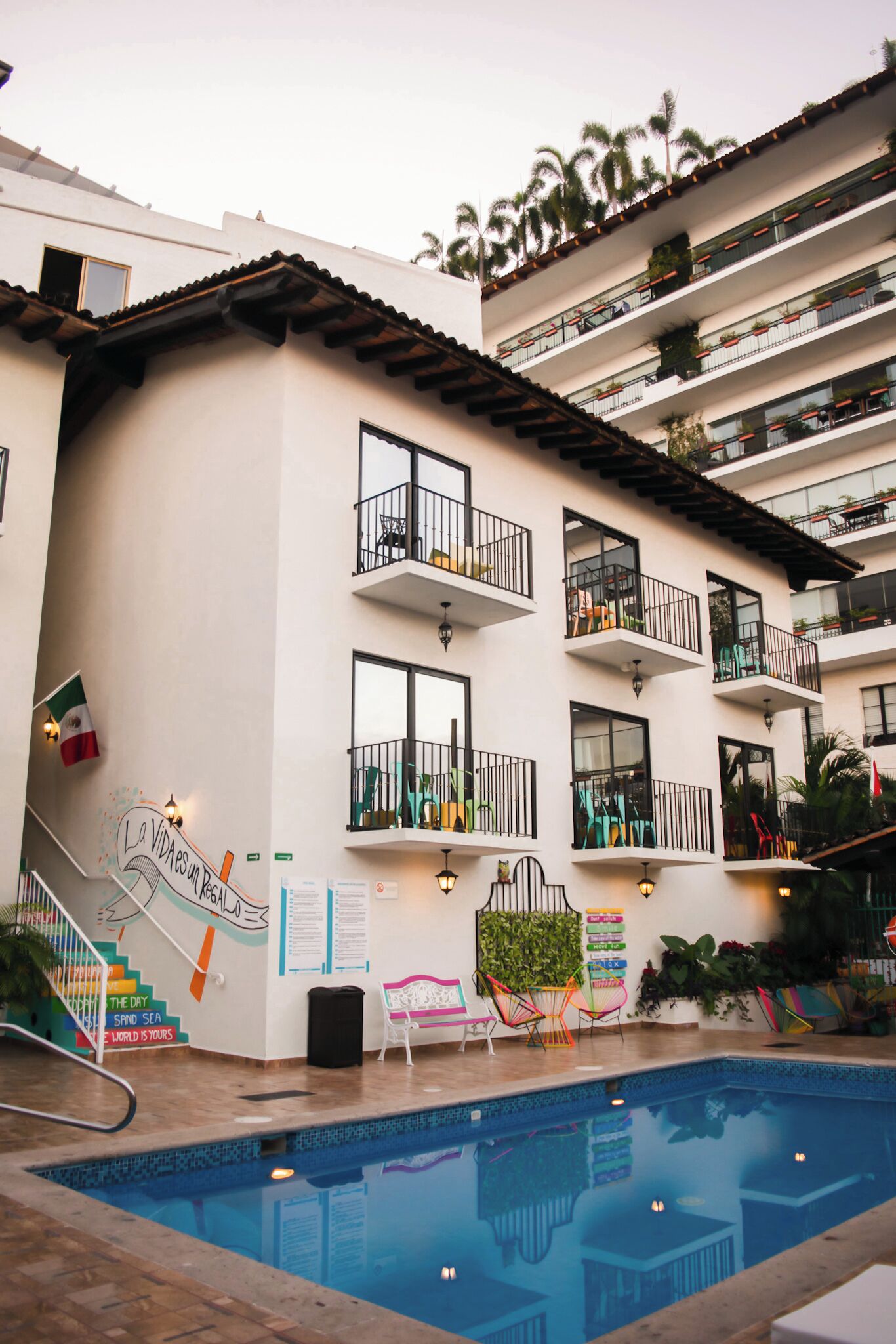 A multi-story hotel with balconies, a swimming pool, and outdoor seating.