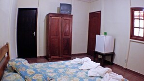A bedroom with a bed, a wooden wardrobe, a small table with a television, and a window. - Hotel Fazenda Rio Formoso (Bonito)