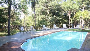 A wooden deck surrounding a rectangular pool with white lounge chairs and a wooden fence. - Hotel Fazenda Rio Formoso (Bonito)