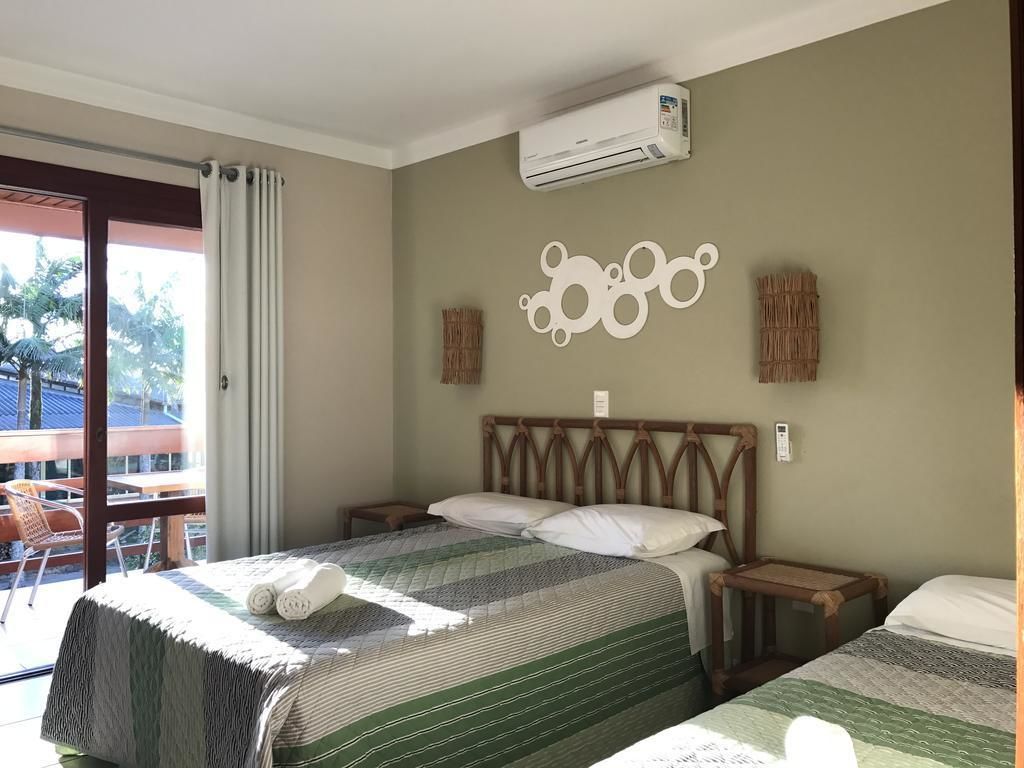 A hotel room with two beds, a large window with curtains, an air conditioning unit, and a decorative wall piece.