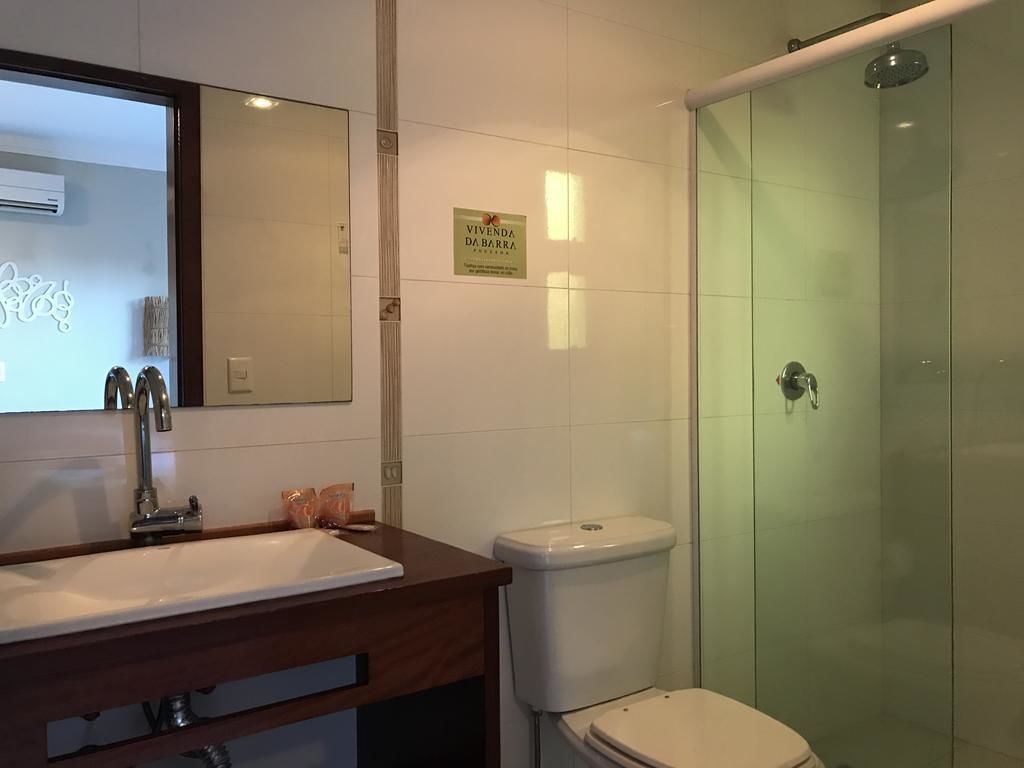 Une salle de bain avec un meuble-lavabo en bois, des toilettes et une douche à parois de verre.