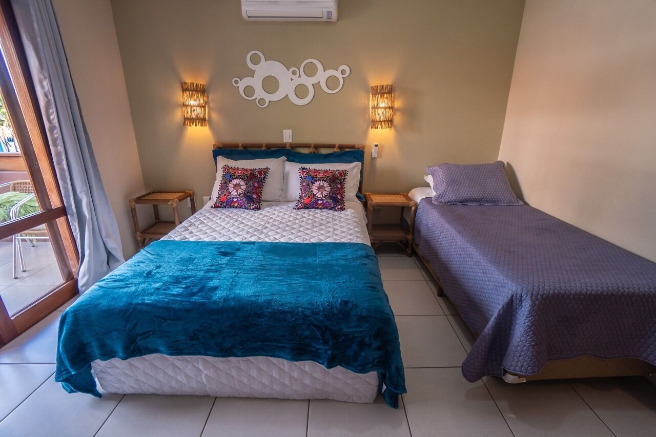 A bedroom with a bed, a bedside table, a lamp, and a window.