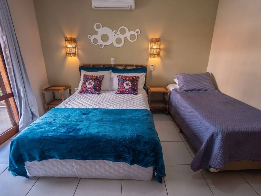 A bedroom with a bed, a bedside table, a lamp, and a window.