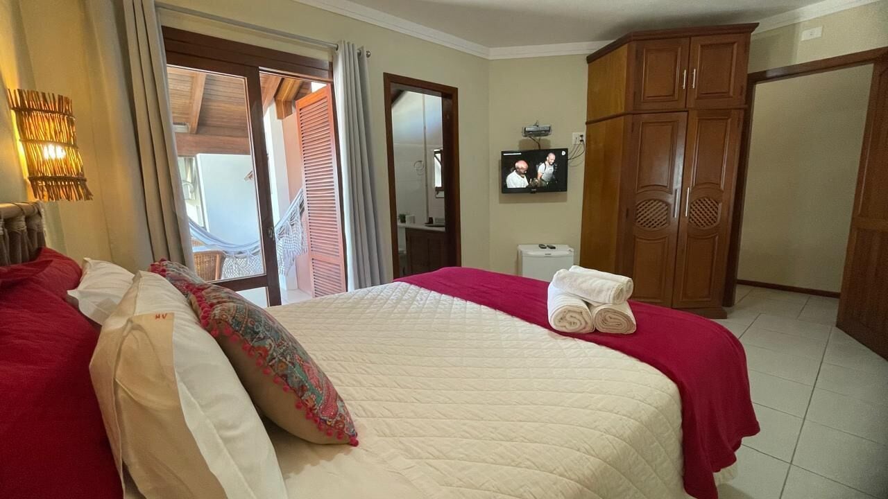 Una habitación de hotel con cama, televisión, armario y baño.