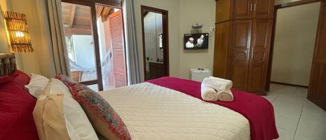 Una habitación de hotel con cama, televisión, armario y baño.