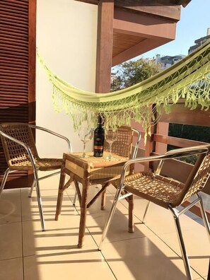 An outdoor seating area with a table, chairs, and a hammock. - Pousada Vivenda da Barra (Torres)