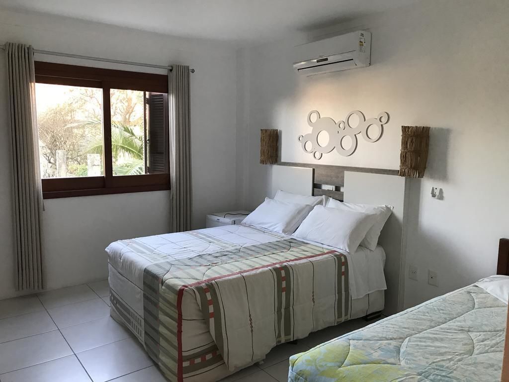 Un dormitorio con cama, ventana con cortinas, unidad de aire acondicionado y un adorno en la pared.