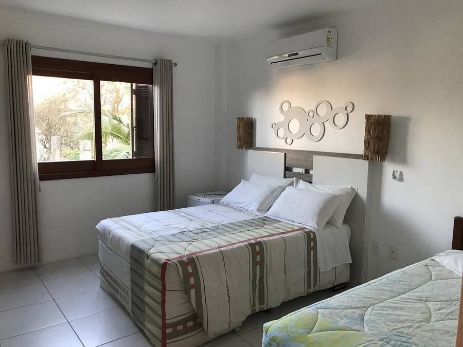 Un dormitorio con cama, ventana con cortinas, unidad de aire acondicionado y un adorno en la pared.