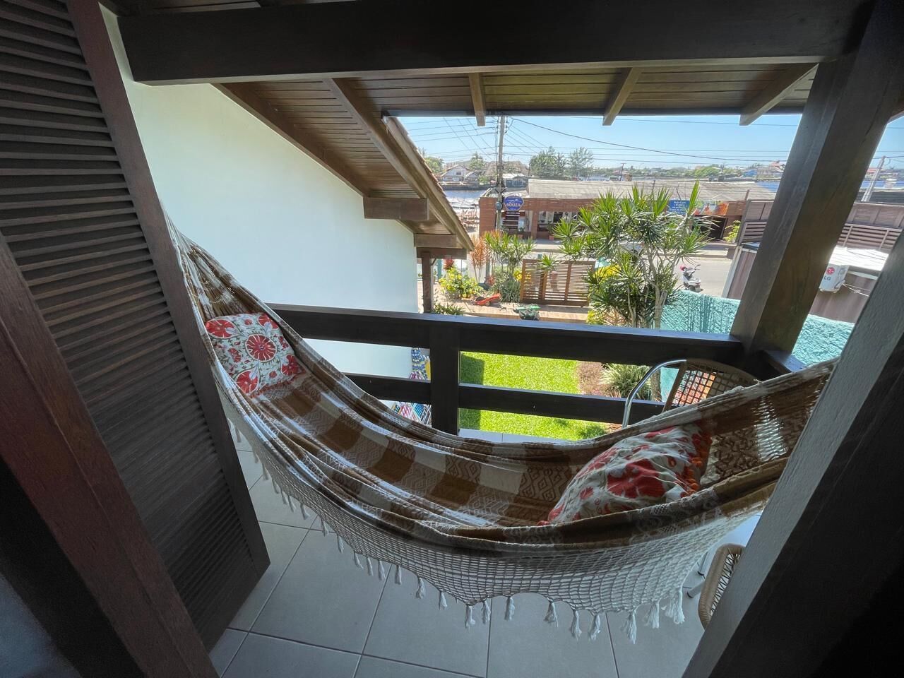 A hammock on a balcony with a view of a residential area.