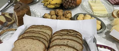 A buffet table with various food items including bread, fruits, and pastries.
