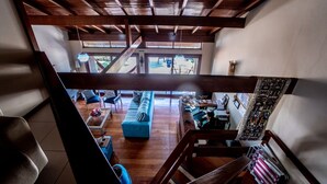 A spacious living area with a blue sofa, wooden beams, and a view of the outdoor area. - Pousada Vivenda da Barra (Torres)