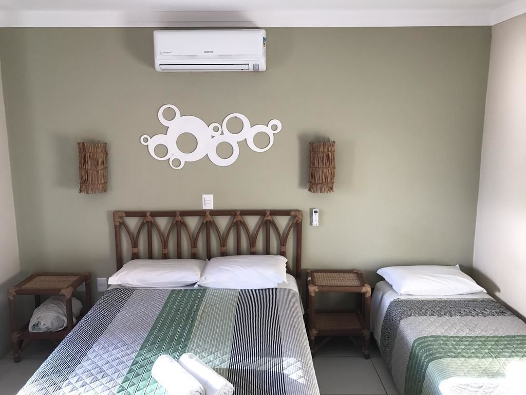 A hotel room with two beds, a wall-mounted air conditioner, and decorative wall art.