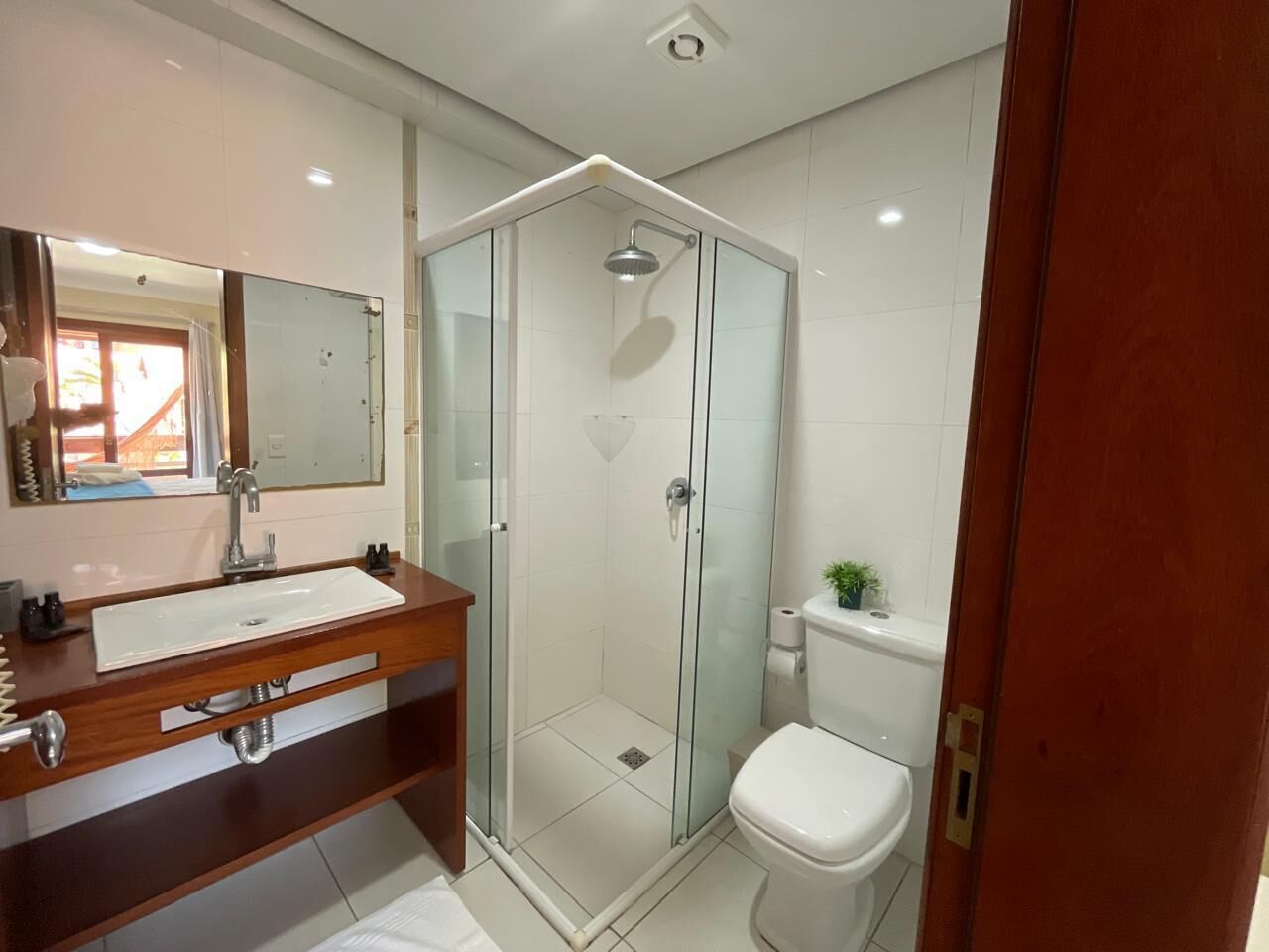 Un bagno moderno con cabina doccia in vetro, un mobile bagno in legno con lavabo e un water.