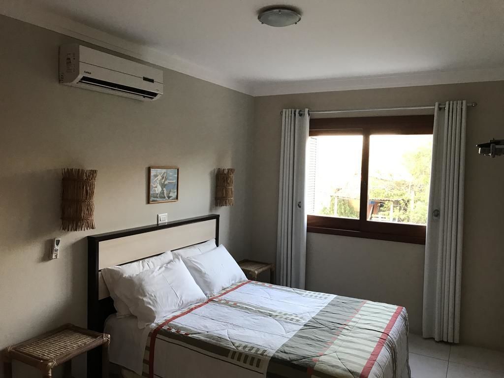 Een slaapkamer met een bed, airconditioning, een raam met gordijnen en een klein nachtkastje.