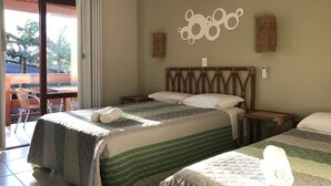 Habitación de hotel con dos camas, cabecero de madera, unidad de aire acondicionado y vista al exterior.
