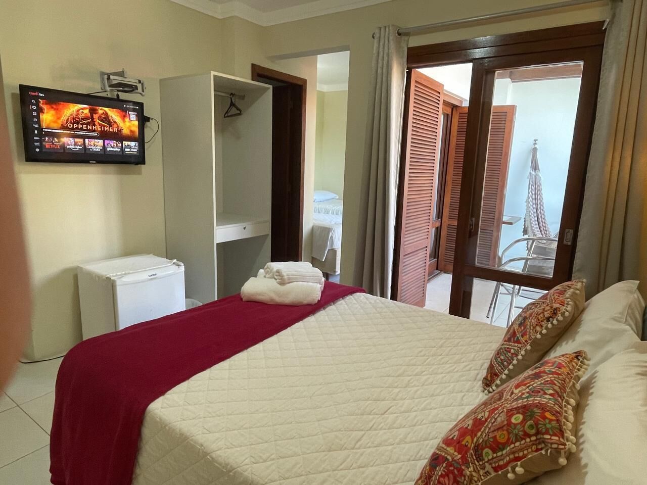 A hotel room with a bed, a television, a wardrobe, and a balcony with a view.