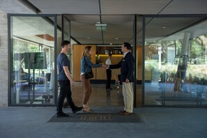 A reception area with a reception desk, a glass door entrance, and a reception area with a sign above the door. - Hotel Las Majadas (Pirque)