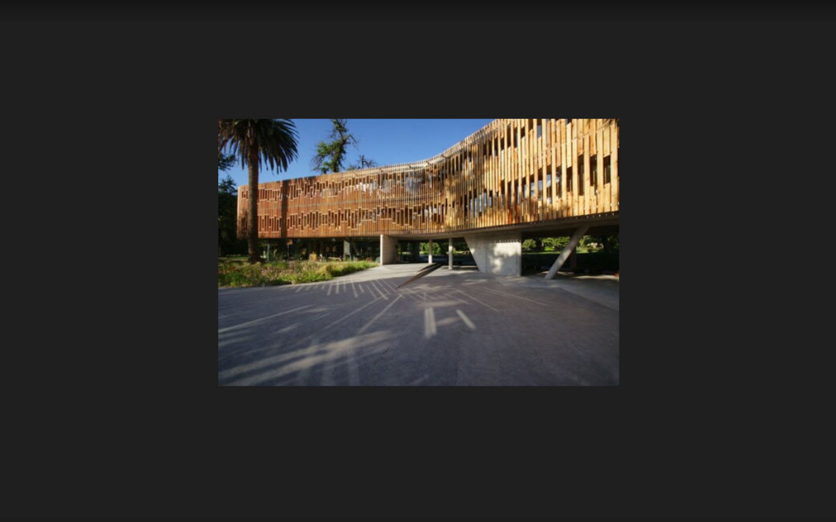 A modern building with a wooden facade and a cantilevered section supported by a concrete base.