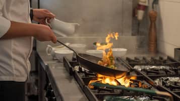 A chef cooking with a wok on a stove, surrounded by multiple bowls.